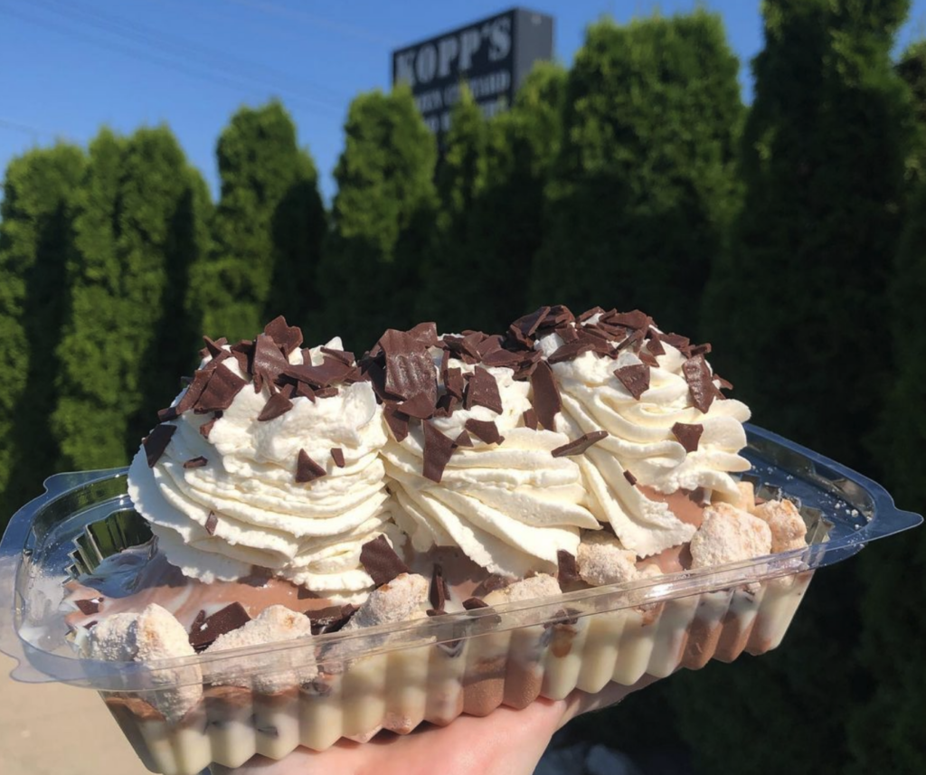 A sundae being held up with the Kopps sign in the background